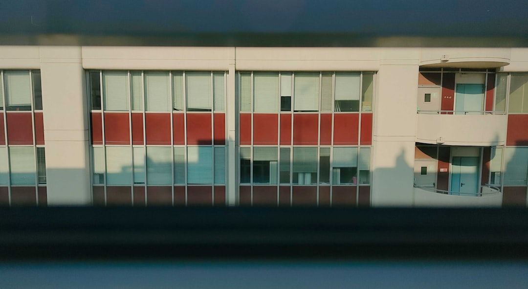 Fönster på en byggnad med röda paneler, speglingar och skuggor.