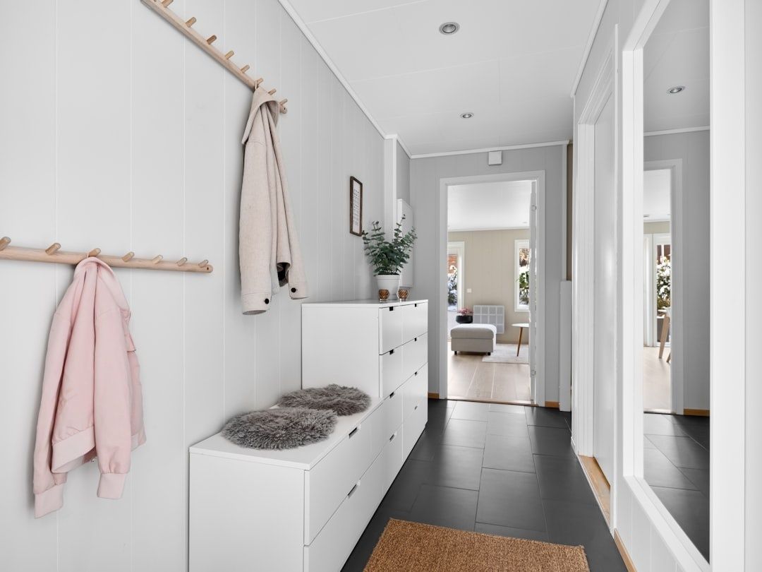Ljus och organiserad hall med krokar, förvaring och sittbänk